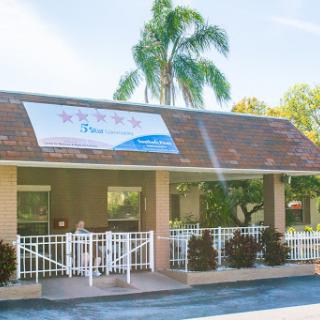 A welcoming commercial building with a prominent banner and surrounding palm trees.