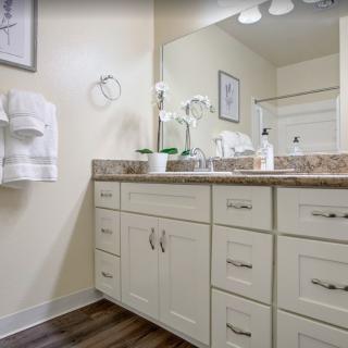 A clean and modern bathroom with a white vanity, large mirror, and decorative elements.