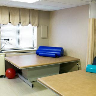 A therapy room with rehabilitation equipment, featuring therapy tables and exercise balls.