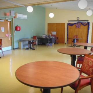 An empty community room with round tables and chairs, decorated for an event.