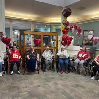 A joyful gathering of seniors celebrating with balloons and smiles.