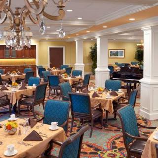 An elegant restaurant dining room with neatly arranged tables and chairs, illuminated by a chandelier.