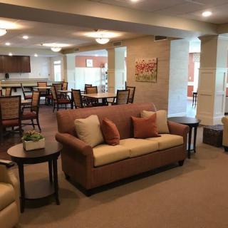 A cozy living room with a sofa and tables, leading to a dining area.