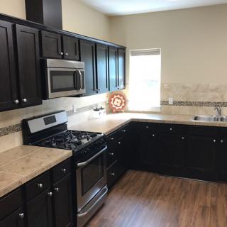 A modern kitchen with dark wooden cabinets, stainless steel appliances, and spacious countertops.