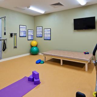 A spacious exercise room equipped with a yoga mat, exercise blocks, gym balls, and a television for workout sessions.