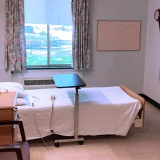 A hospital room featuring a bed, medical equipment, and a window with curtains.