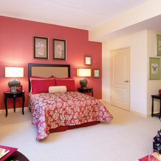 Cozy bedroom featuring a red accent wall and artistic decor.