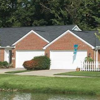 A suburban house with a brick facade, two garages, and a front yard.