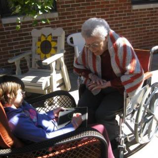 An elderly woman in a wheelchair interacting with a child outdoors.