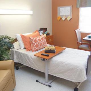 A cozy hospital room with a bed, bedside table, and comfortable seating.