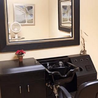 A salon hair wash station with a large mirror and sink.
