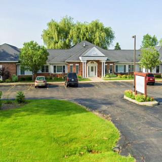 Exterior view of a medical clinic with a parking lot and surrounding greenery.