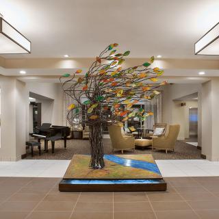 A modern lobby featuring an intricate tree sculpture as its centerpiece.