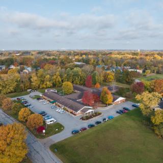 A scenic aerial view of a building surrounded by vibrant autumn foliage.