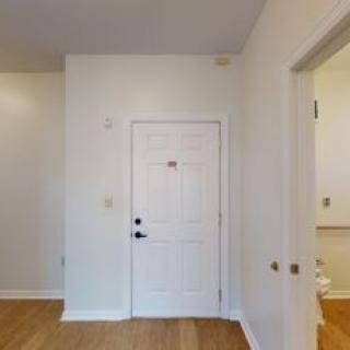 An interior view of a room with a white door and wooden flooring.