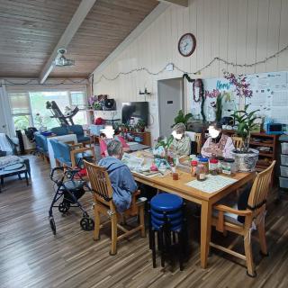 A cozy living space with people gathered around a dining table engaged in activities.