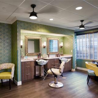 A modern salon interior featuring stylish furniture, large mirrors, and bright lighting.
