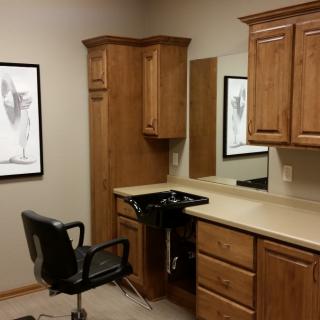 A cozy hair salon setup with a barber chair and wooden cabinetry.