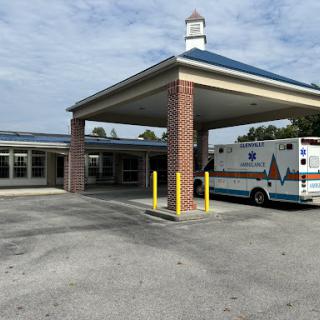 An ambulance parked at the entrance of a medical facility on a cloudy day.