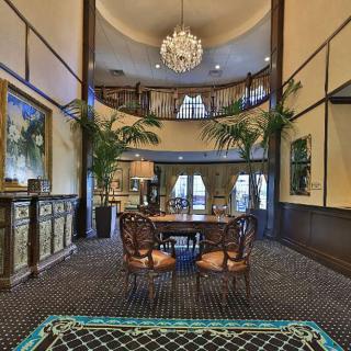 A luxurious dining area with elegant furniture, featuring a grand chandelier and high ceilings.