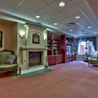 A cozy living room featuring a fireplace, comfortable seating, and elegant shelves.