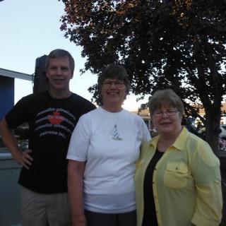 A group of three people posing for a photo outdoors in casual clothing.