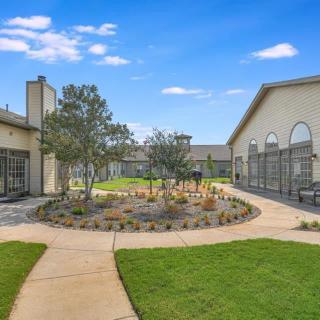 A landscaped courtyard with pathways and greenery between buildings under a clear blue sky.