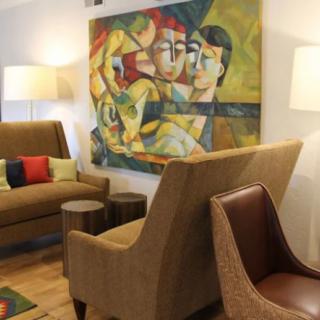 A modern living room featuring stylish furniture and an abstract painting on the wall.