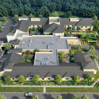 Aerial view of a modern building surrounded by greenery and trees.