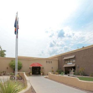 A building entrance with flags and a cloudy sky.