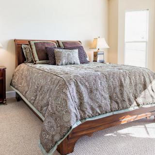 A well-appointed bedroom with a neatly made bed, decorative pillows, and a bedside lamp.