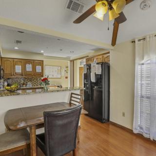 A cozy kitchen and dining area with wooden flooring, featuring a ceiling fan, refrigerator, and a dining table with chairs.