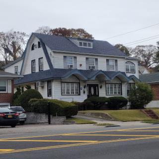 A charming two-story house with a distinctive architectural style and well-maintained front yard.