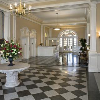 Elegant hotel lobby with checkered floors and a central floral arrangement.