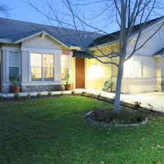 A cozy home with a well-maintained lawn and evening lights illuminating the exterior.