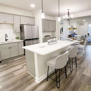 A modern kitchen featuring white cabinets, a central island with seating, and stainless steel appliances in an open floor plan.
