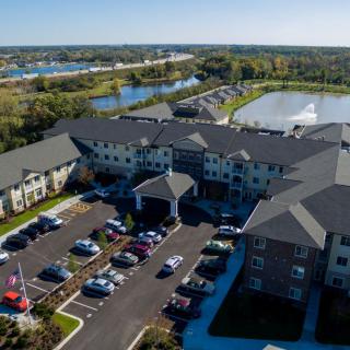 Aerial view of a residential apartment complex with a parking lot and nearby lake.