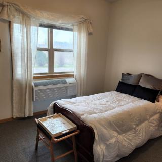 A minimalist bedroom with a neatly made bed next to a window and nightstand.