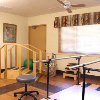 A physical therapy room equipped with exercise bars, a chair, and rehabilitation tools.