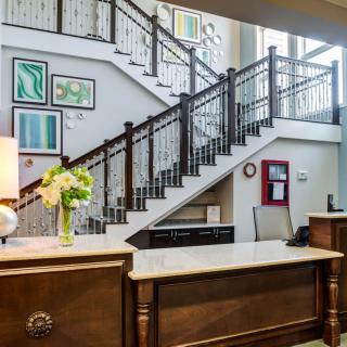 A welcoming reception area featuring a wooden desk, decorative artwork on the wall, and a staircase leading to an upper floor.