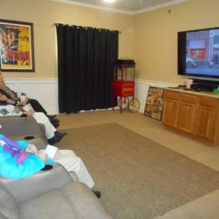 Seniors seated in a living room watching television.