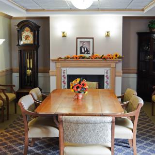 A well-appointed dining room with a wooden table, surrounded by chairs and featuring a fireplace adorned with seasonal decorations.