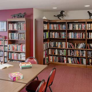 A cozy library corner with tables, chairs, and rows of bookshelves filled with books.