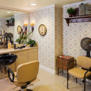 A cozy hair salon interior featuring chairs, a large mirror, and stylish decor.