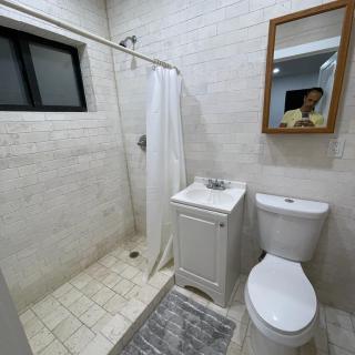 A small, modern bathroom with a shower, sink, and toilet.
