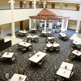 An empty indoor dining area with neatly arranged tables and chairs, featuring subtle decor and warm lighting.
