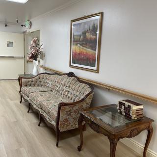 A hallway with a classic sofa and table, adorned with books and a painting on the wall.
