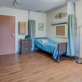 A simple hospital room with a bed, curtains, and minimal furniture.