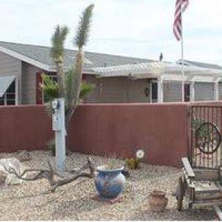 A desert-style yard in front of a house, featuring cactus plants and an American flag.