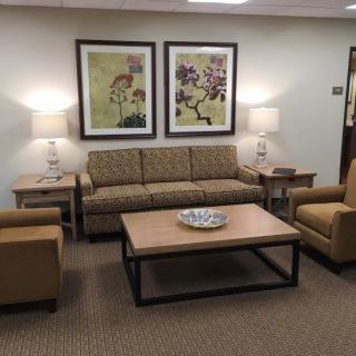 A cozy waiting room featuring a sofa, chairs, coffee table, and decorative artwork.